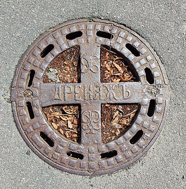 Old manhole cover in St. Petersburg with pre-revolutionary spelling