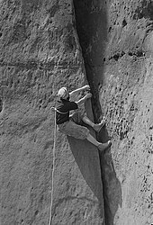 Un grimpeur gravissant une fissure avec une corde autour du torse