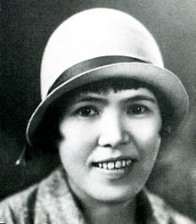 Photo noir et blanc du visage d'une femme portant un chapeau blanc.