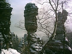 Dos pilates de piedra estratificada parcialmente cubiertos en nieve. Montañas de Arenisca del Elba, Alemania.