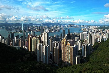 panorama: looking down on a city of skyscrapers, land mass in the distance separated by a body of water.
