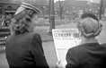 Two young women standing on Saint Catherine Street in Montreal, read the front page of The Montreal Daily Star. The title "Germany Quit" announces the German surrender and the impending end of the World War II in Europe.