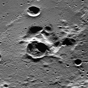 Oblique view facing east with the dark interior crater near center, showing that the dark crater is adjacent to a complex depression