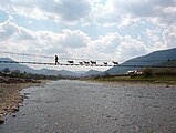Кози, що рухаються по мосту над гірською річкою в Карпатах