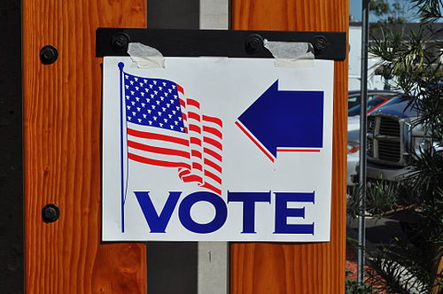 A sign with the U.S. flag, the word VOTE and a blue arrow