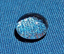Setetes air bulat mengkilap di atas kain biru