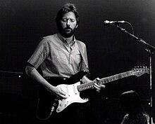 Una foto in bianco e nero di Eric Clapton con una chitarra durante un concerto
