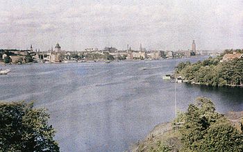 En vy från Långholmen över Riddarfjärden mot öst med Stockholms rådhus och Stockholms stadshus i bakgrunden. I november 1935 förändrades stadslandskapet när Västerbron invigdes. Fotografiet från 1926 är taget av Gustaf W. Cronquist på en autochromplåt.