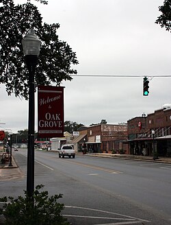 View of the main street of Oak Grove, looking west from the town square, with a "Welcome to Oak Grove" sign in the foreground