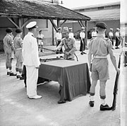 Seorang pimpinan Jepang menyerahkan senjatanya kepada Letnan Britania dalam sebuah upacara di Saigon.