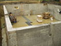 Типични стамбени темељ од ливеног бетона, осим одсуства анкерских вијака. Бетонски зидови су ослоњени на континуалне темеље. Ту је и под од бетонске плоче. Обратите пажњу на стајаћу воду у француским одводним рововима по ободу.