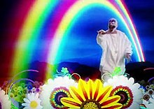 member of Insane Clown Posse dancing in an animated field of flowers beneath a simplistic digital rainbow.