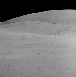 Лунный модуль «Орион» вдали (слева внизу). Видна скала House Rock, огромный валун на краю кратера Северный Луч (чуть выше и правее центрального перекрестия). Снимок сделан Чарли Дьюком со Station 4 на камеру с 500-мм объективом