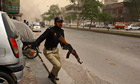 A policeman advancing towards a firefight at an Ahmadi mosque in Lahore