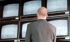 Businessman looking at a wall of television sets