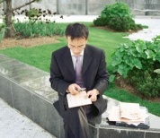 An Asian businessman sits outside, looking at documents 