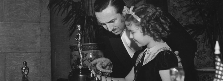 Walt Disney receives one statuette and seven miniature statuettes from Shirley Temple for "Snow White."