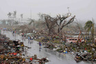 Resident walk past damaged houses in Tacloban city, Leyte province, central Philippines. Photo / AP