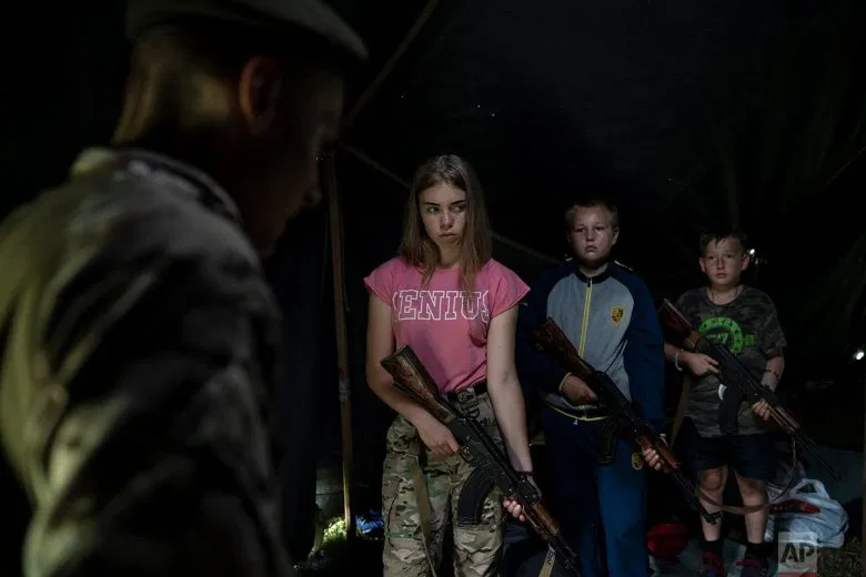 Participants of the "Temper of will" summer camp, organized by the nationalist Svoboda party, hold their AK-47 riffles as they receive instructions during a tactical exercise on July 28, 2018, in a village near Ternopil, Ukraine. Campers as young as 8 years old practice using assault rifles. They are taught to shoot to kill Russians and their sympathizers. (AP Photo/Felipe Dana)