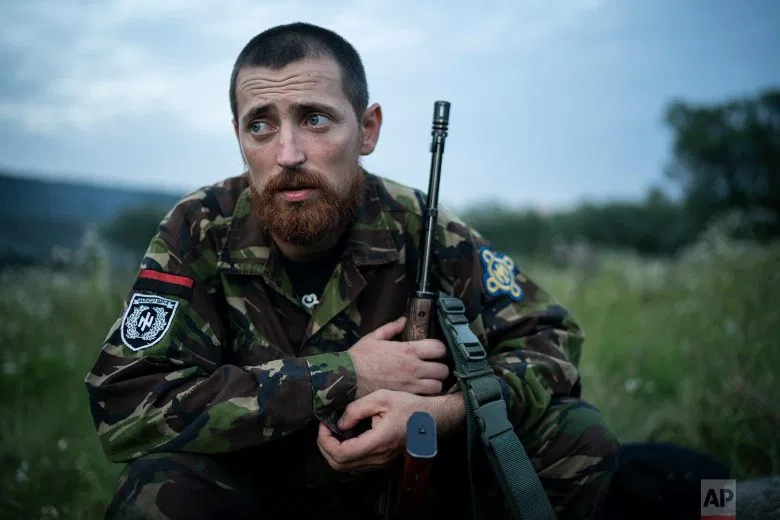 Yuri "Chornota" Cherkashin, head of Sokil (Falcon), the youth wing of the nationalist Svoboda party, sits with his AK-47 rifle at the "Temper of will" summer camp on July 29, 2018, in a village near Ternopil, Ukraine. âWe never aim guns at people,â he tells his campers. âBut we donât count separatists, little green men, occupiers from Moscow as people, so we can and should aim at them.â (AP Photo/Felipe Dana)