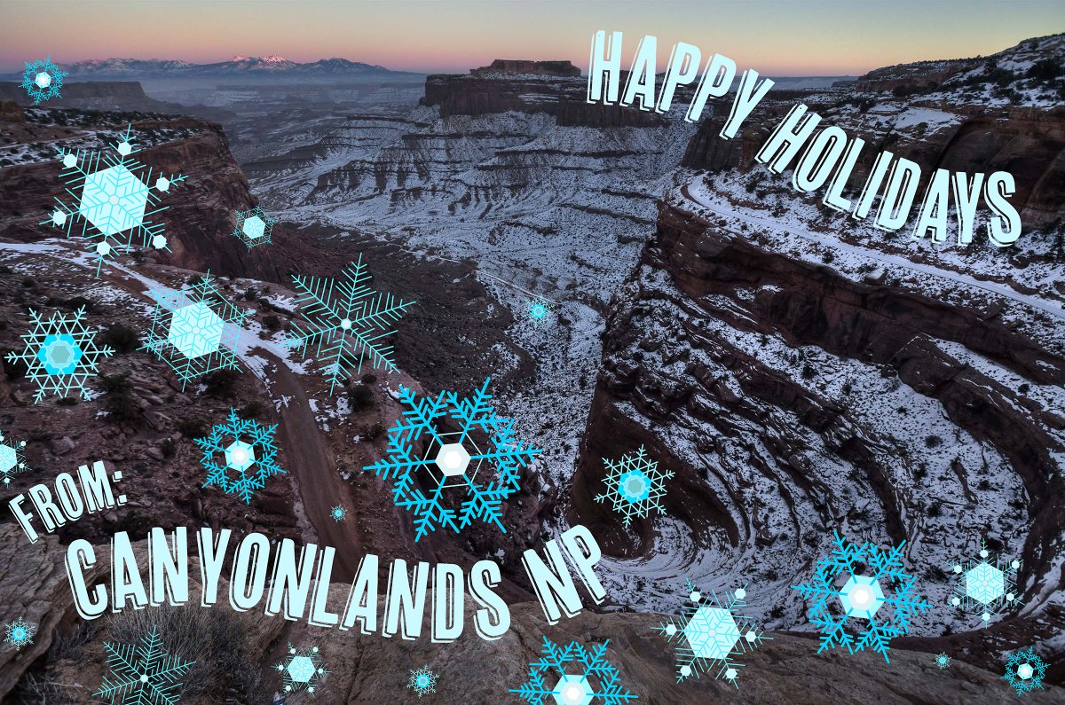Blue and white snowflakes swirl atop a background image of a view of snow covered Shafer Canyon at sunrise. The holiday card style image reads, "Happy Holidays from Canyonlands NP." 
