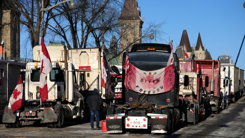 A person walks among trucks in Ottawa, on Monday, Feb. 14, 2022. THE CANADIAN PRESS/Justin Tang