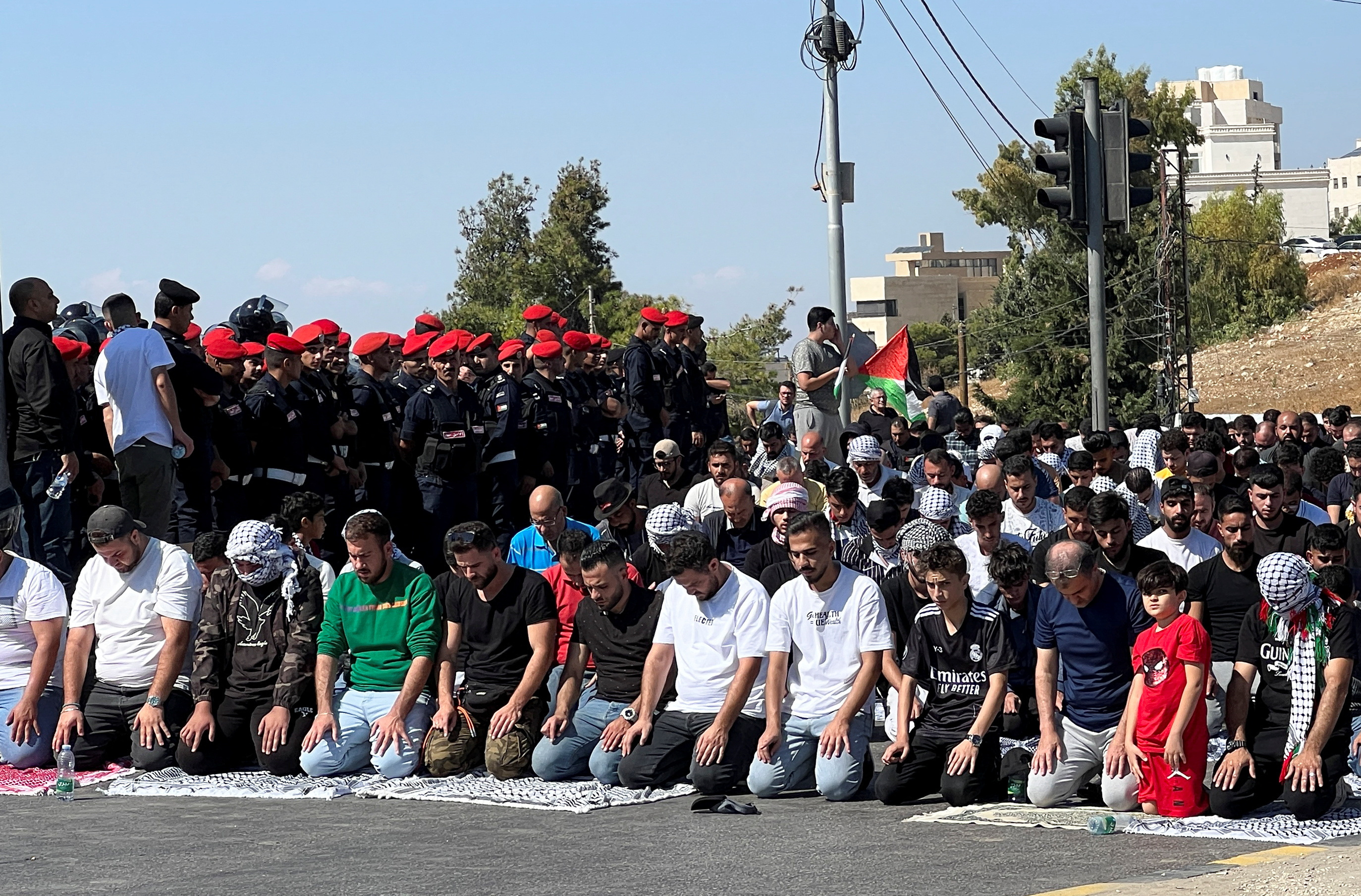 Men pray as security forces stand guard during a protest to express solidarity with Palestinians, in Amman