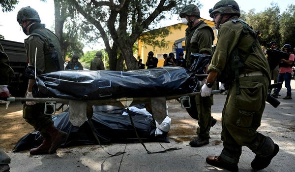 Israeli soldiers carry out bodies Tuesday of those murdered by Hamas at Kibbutz Kfar Azza.