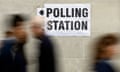 Blurred people walking past a in-focus ‘polling station’ sign.