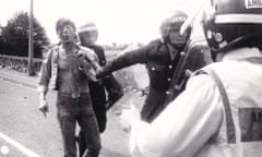 A police officer pulls a bloodied miners by the shirt surrounded by other officers