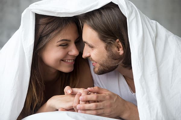 Ein Paar weiß, welche Fruchtbarkeits-Mythen wahr und welche falsch sind, und steckt gelassen die Köpfe unter der Bettdecke zusammen.