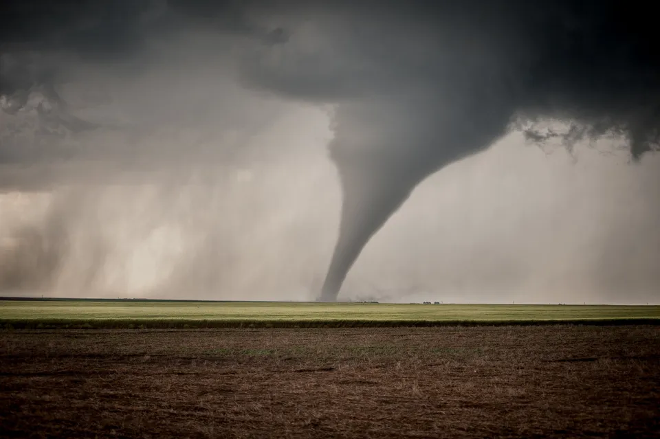 A photograph of a large tornado over an open grassy expanse