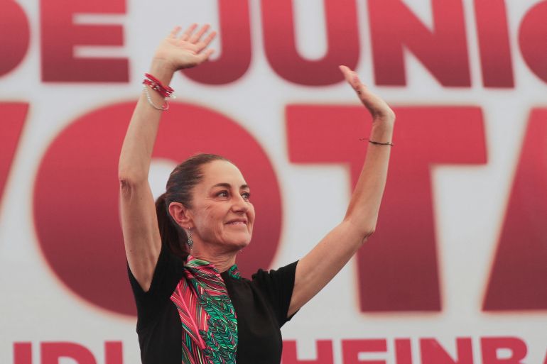 Claudia Sheinbaum raises both arms from the stage at a campaign rally.