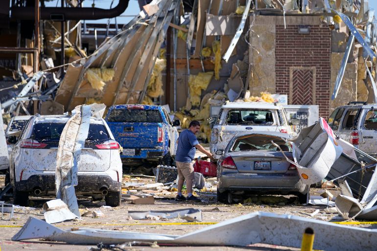 A man looks at a damaged car after a tornado hit in the US