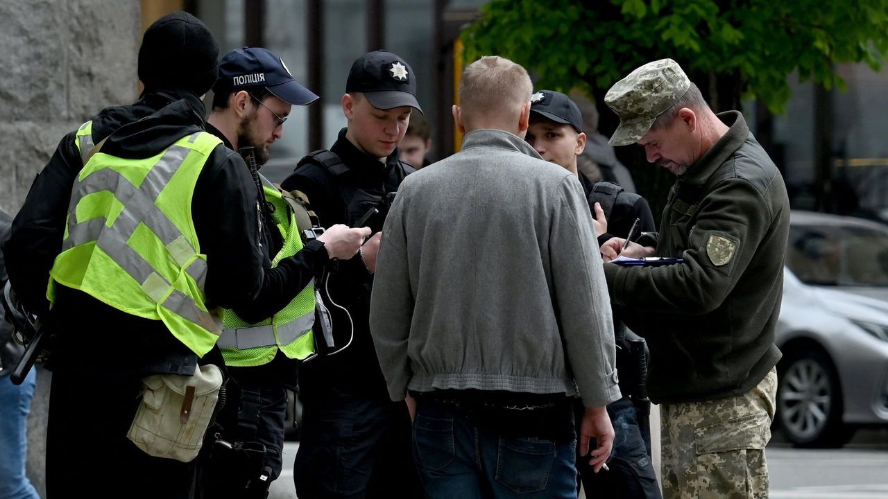 Ukrainian serviceman and police officers check the documents of a man in the center of Kyiv