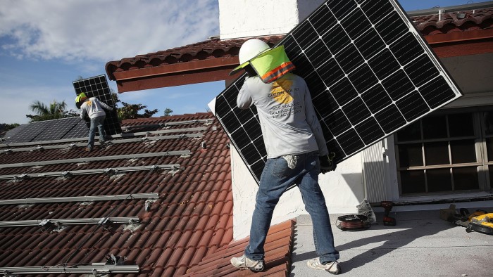 Workers install a solar panel system on the roof of a home
