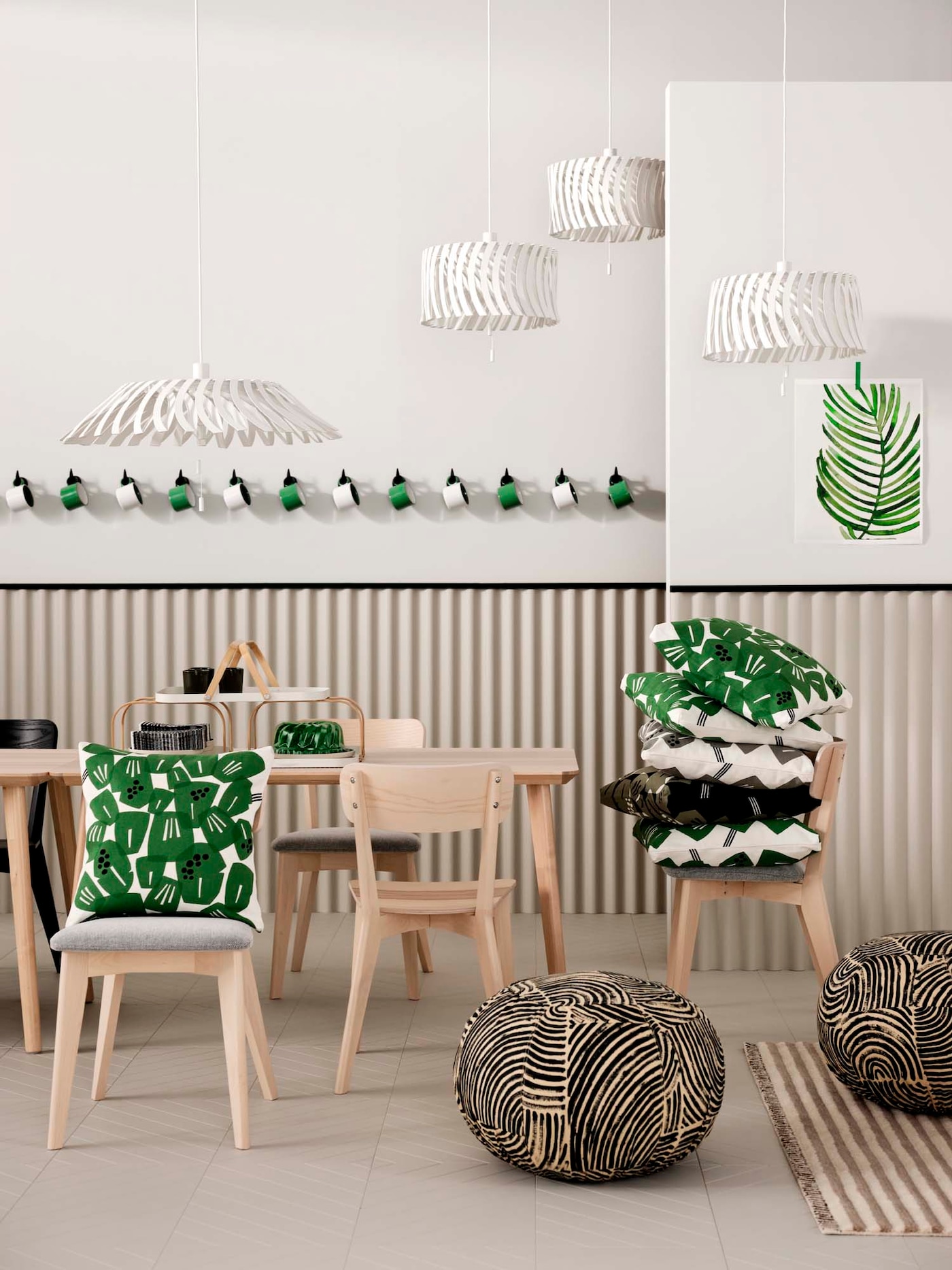 LISABO chairs are placed around a LISABO table. Some chairs are piled with cushions and four pendant lamps hang from above.