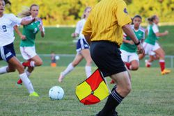 Soccer game in action with referee on the field.
