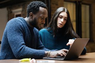 Man and woman use laptop together 