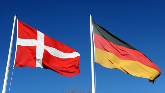 Die deutsche und die dänische Flagge wehen vor blauem Himmel. © dpa Foto: Carsten Rehder