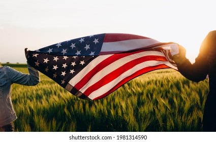  4th of july Patriotic holiday. Independence day. Hands holding american flag at sunse.  Stock Photo