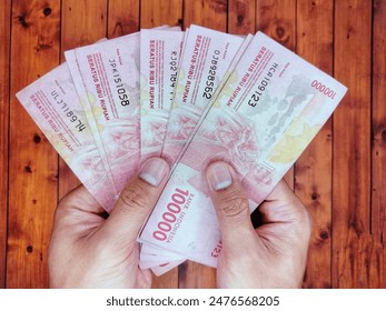 両手に持つインドネシアの紙幣10万枚の写真素材
