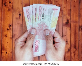 両手に持つインドネシアの紙幣10万枚の写真素材