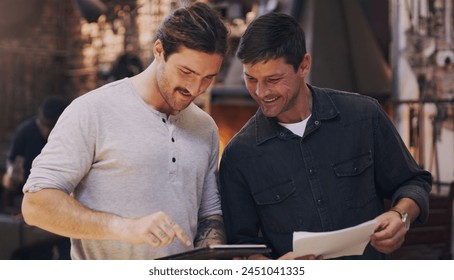 Tablet, partner and men in workshop for discussion or blacksmith planning in small business startup. Metal work, smile and team in factory on technology, paperwork or collaboration for manufacturingの写真素材