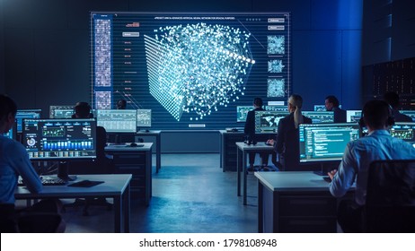 プロのコンピューター・データ・サイエンス・エンジニアのチームは、グラフ、グラフ、インフォグラフィック、テクニカル・ニューラル・ネットワーク・データ、統計を示す画面を備えたデスクトップで作業を行います。 暗い制御と監視室。の写真素材