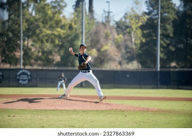 teen baseball player pitcher in blue uniform in full wind up on the mound 庫存照片