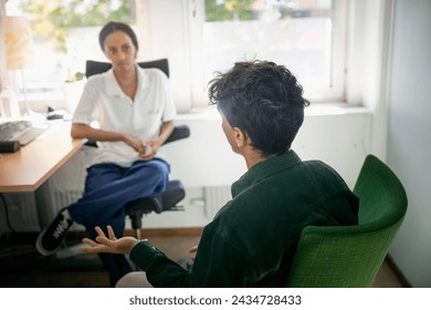 オフィスでの心理療法セッション中に女性カウンセラーと話す十代の少年の写真素材