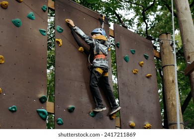 adolescent grimpant sur le mur dans un parc d'aventures en plein air passant un parcours d'obstacles. parc à cordes hautes : photo de stock