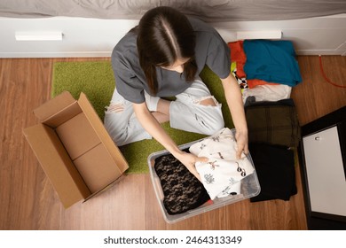 Teenage student packing things to move, packing up memories and essentials, dorm room farewell, college relocation.: stockfoto