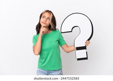 Teenager Russian girl isolated on blue background holding a question mark icon and having doubts Stock-foto
